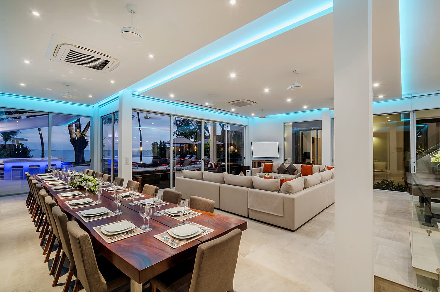 Long dining table and lounge lit at dusk